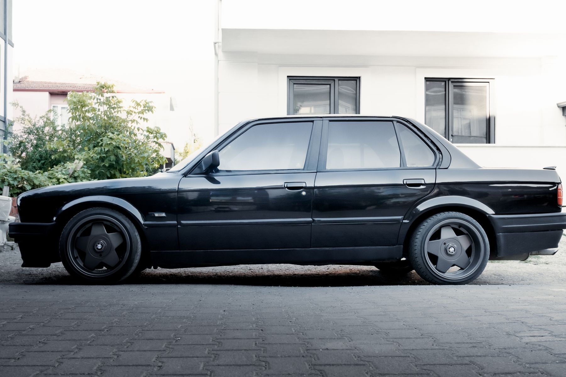 Stanced black BMW E30 gusheshe, side profile